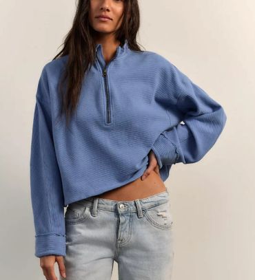 Person wearing a blue half-zip sweater and light jeans.