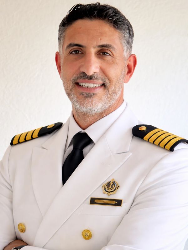 Smiling naval officer in white uniform with captain insignia.