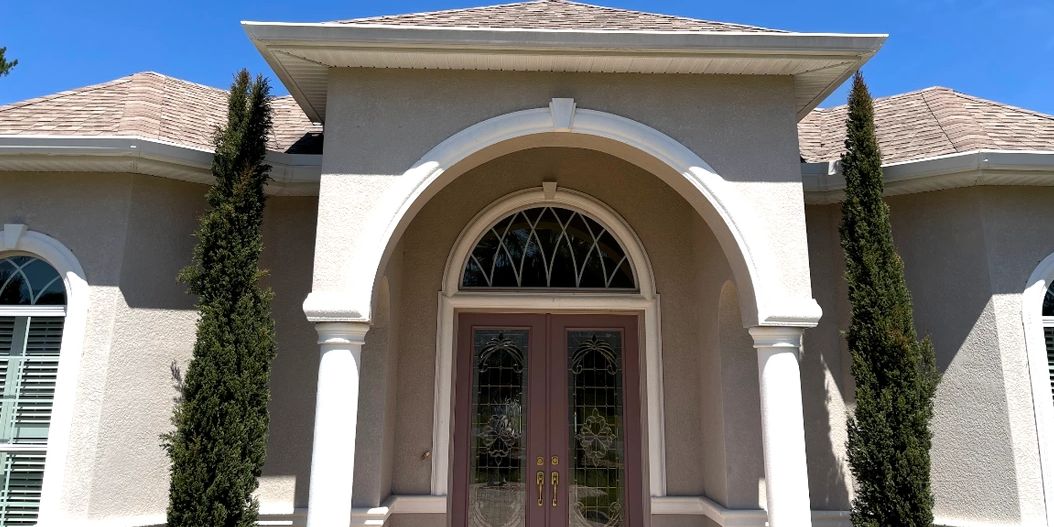 Elegant entrance with arched doorway and tall cypress trees.
