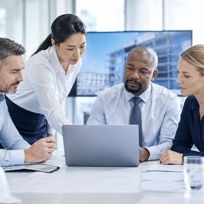 Four business professionals collaborating over a laptop in a meeting room.