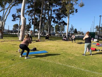 Group exercising outdoors on a sunny day.