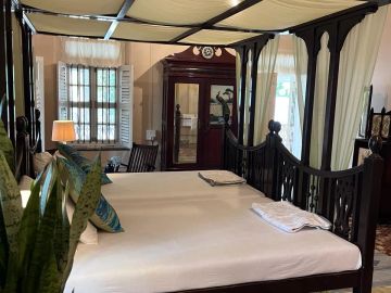 A cozy vintage bedroom with a dark wooden canopy bed.