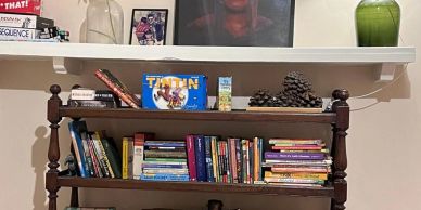 Bookshelf with books and decorative items under a white shelf.