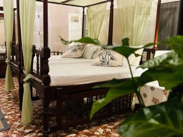 Elegant wooden canopy bed with white curtains in a cozy room.