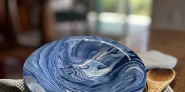 A blue and white marbled ceramic plate on a cloth with a wooden spoon.