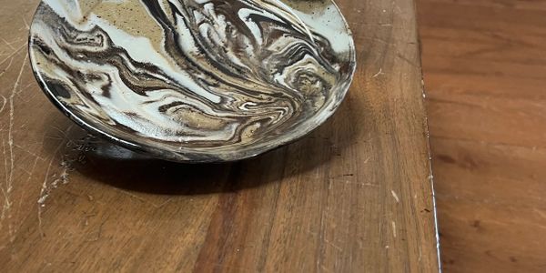 A marbled ceramic bowl on a wooden surface with scratches.