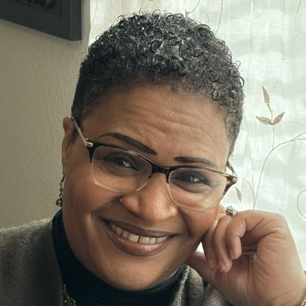 Smiling woman with glasses and short curly hair.
