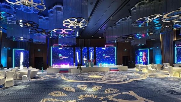 A large, modern event hall with blue lighting and decorated ceiling.