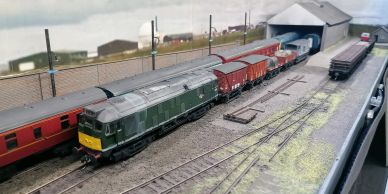 Model train on detailed tracks and freight cars.