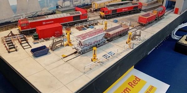 Detailed model train setup with red locomotives and cargo wagons on tracks.