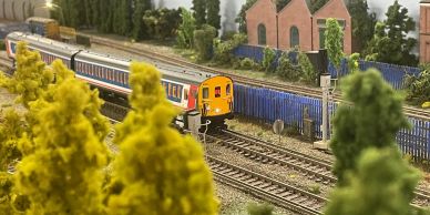 Model train on detailed miniature railway track.