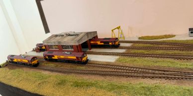 Model trains on tracks with a small depot and crane.