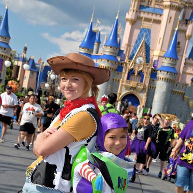 Two children dressed as Woody and Buzz Lightyear at a Disney castle.