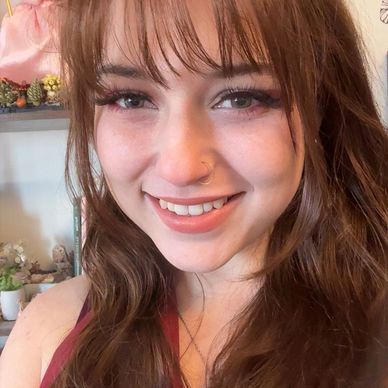 Smiling young woman with long brown hair and a nose ring.