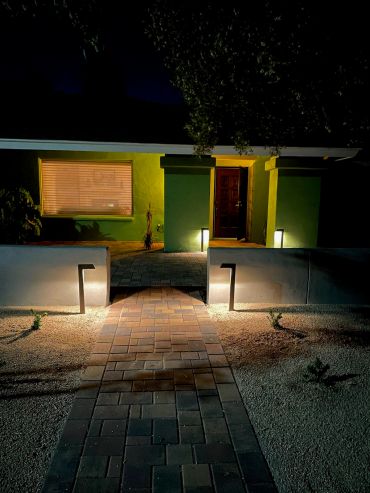 Illuminated pathway leading to a house entrance at night.