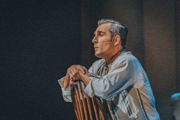 Man resting on a wooden chair, deep in thought.