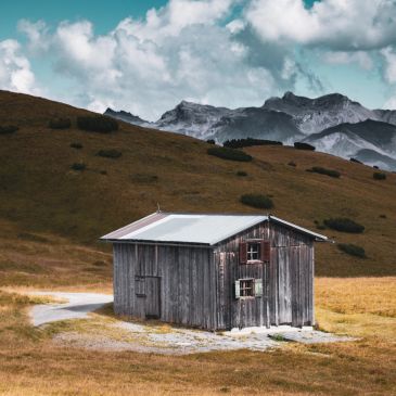 Rustic wooden cabin in a mountain meadow.