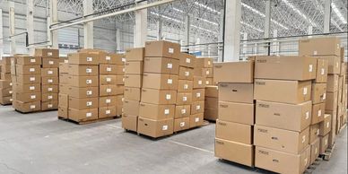Stacks of cardboard boxes neatly arranged on pallets in a spacious warehouse.