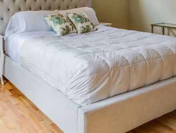 Una cama impecable con colchón y somier, en una habitación iluminada y fresca