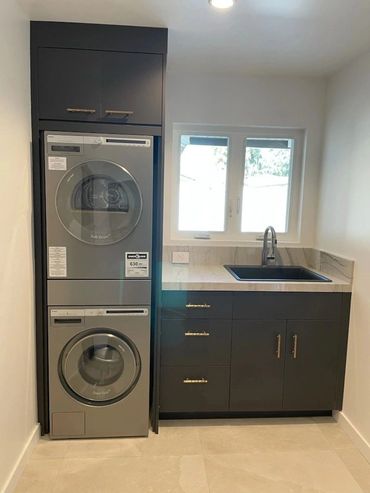 Laundry room with stacked washer and dryer and dark cabinets