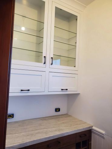 White built-in hutch with glass cabinets over desk