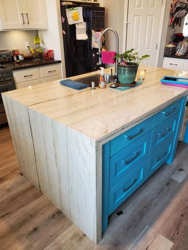 Teal kitchen island with stone waterfall top