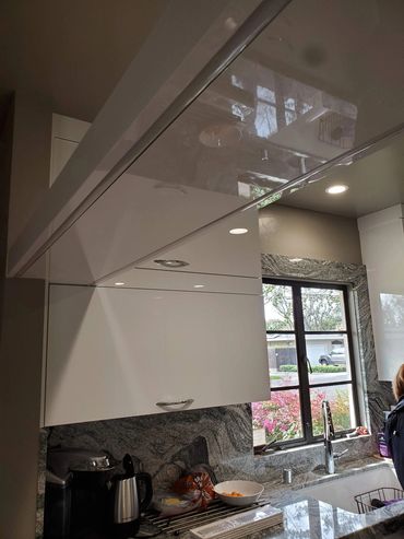 Gloss white kitchen cabinets with stone backsplash
