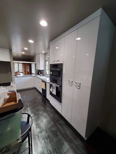 Gloss white tall kitchen cabinets with built-in ovens