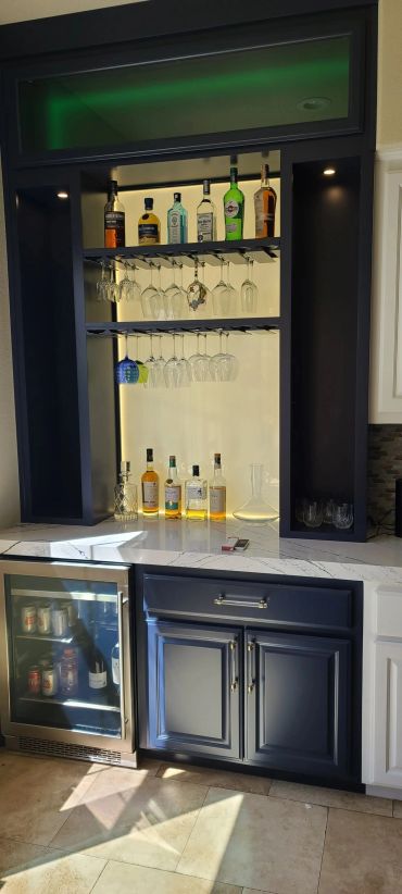Navy built-in bar with lighted glass shelves