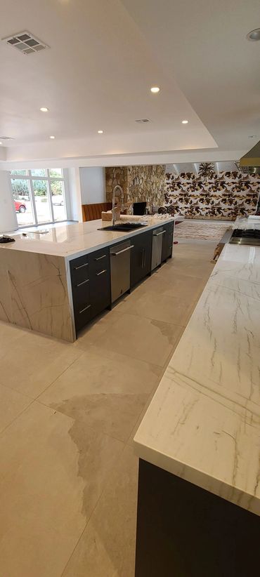 Large kitchen with dark cabinets and marble island