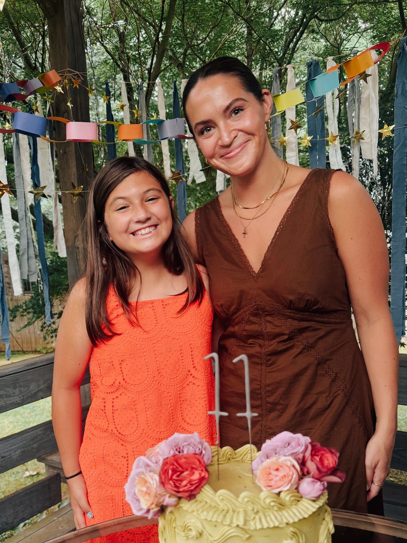 Two females smiling next to a birthday cake with '11' candles.