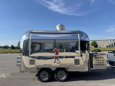 Shiny silver camper trailer reflecting the surroundings on a clear day.