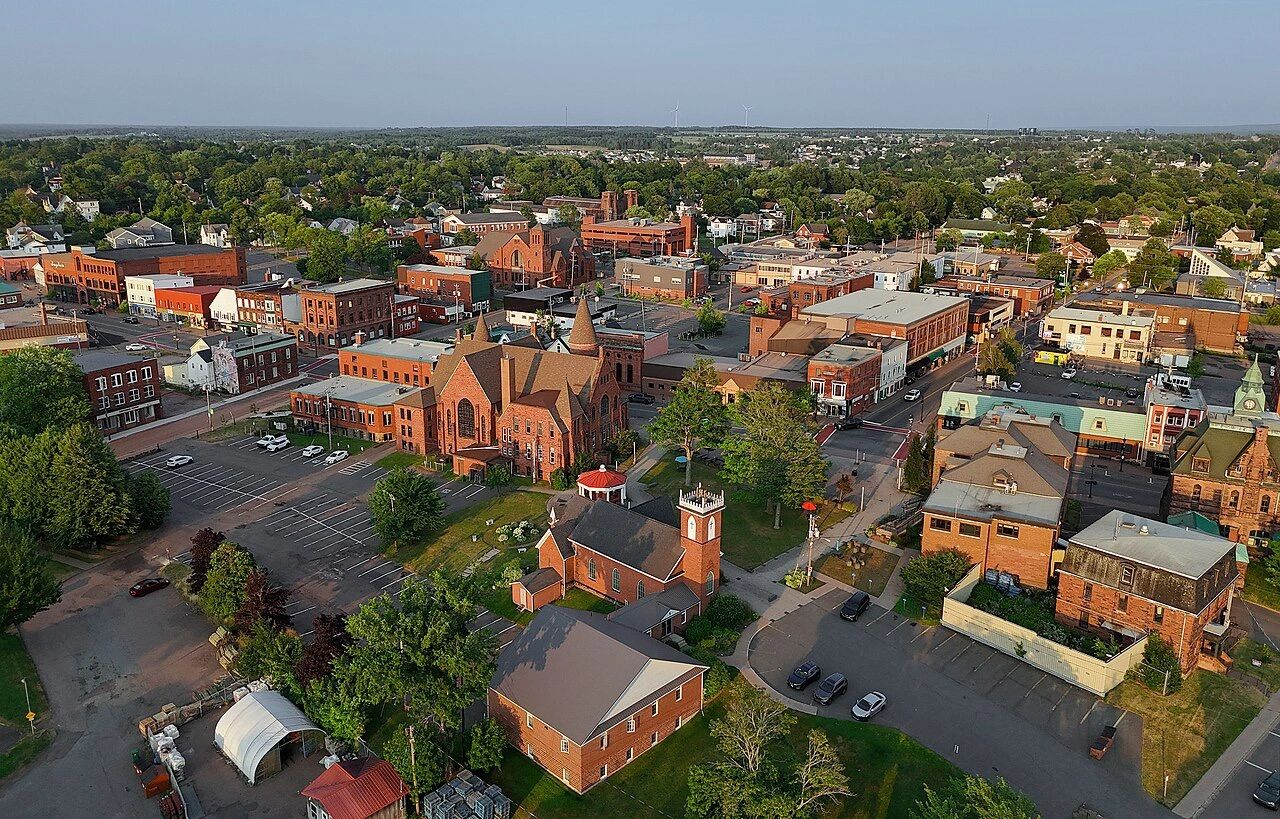 Aerial view of a small town with historic brick buildings and green trees.