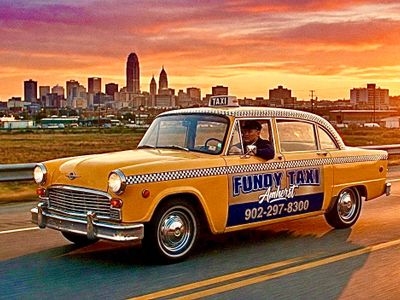 Vintage yellow taxi driving on a road at sunset with city skyline in the background.