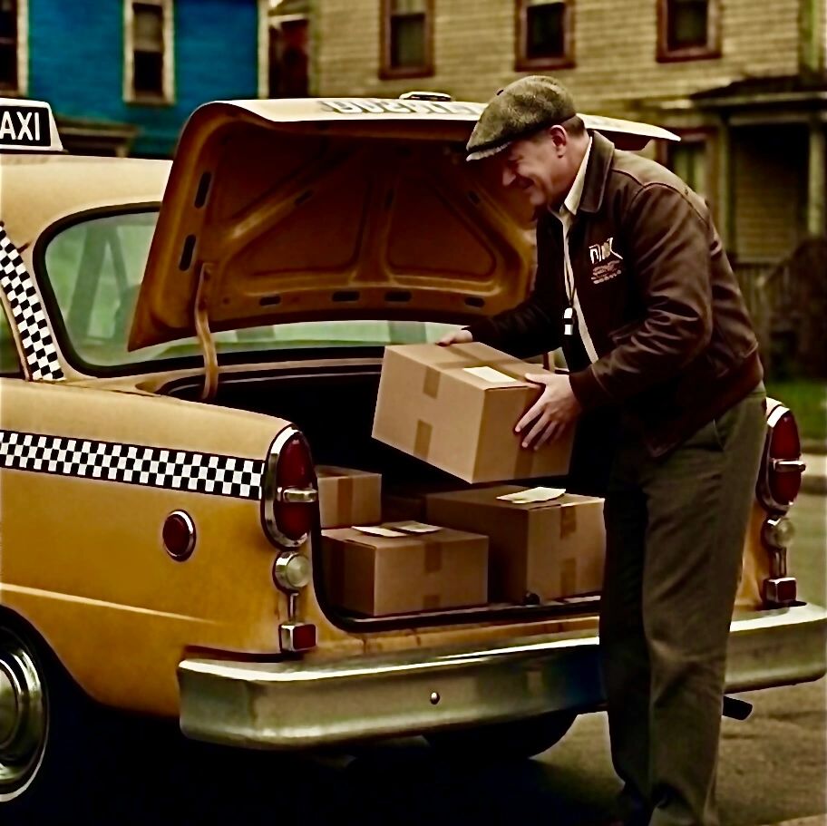 Man loading boxes into the trunk of a vintage yellow taxi.