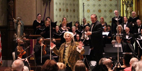 A classical singer performs with orchestra and choir in a grand venue.