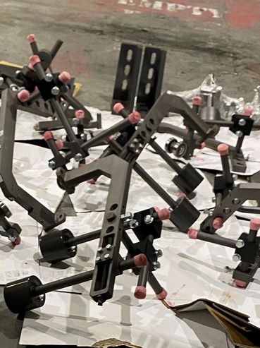 Metal mechanical parts with pink rubber tips on a workshop floor.