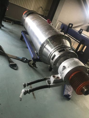 Large cylindrical industrial machine component on a blue stand indoors.