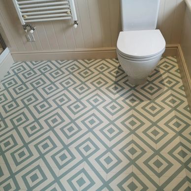 Bathroom floor with blue and white geometric patterned tiles and a white toilet.