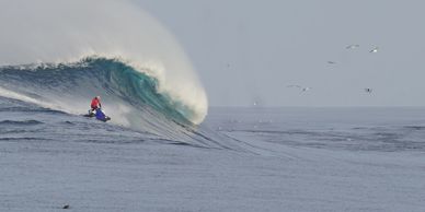 Man on jet ski riding next to large wave