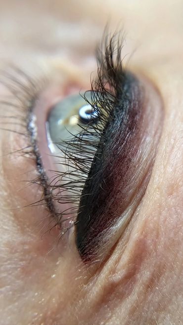 Close-up macro image of one eye immediately after Smoky Permanent Eyeliner procedure, blue-ish iris