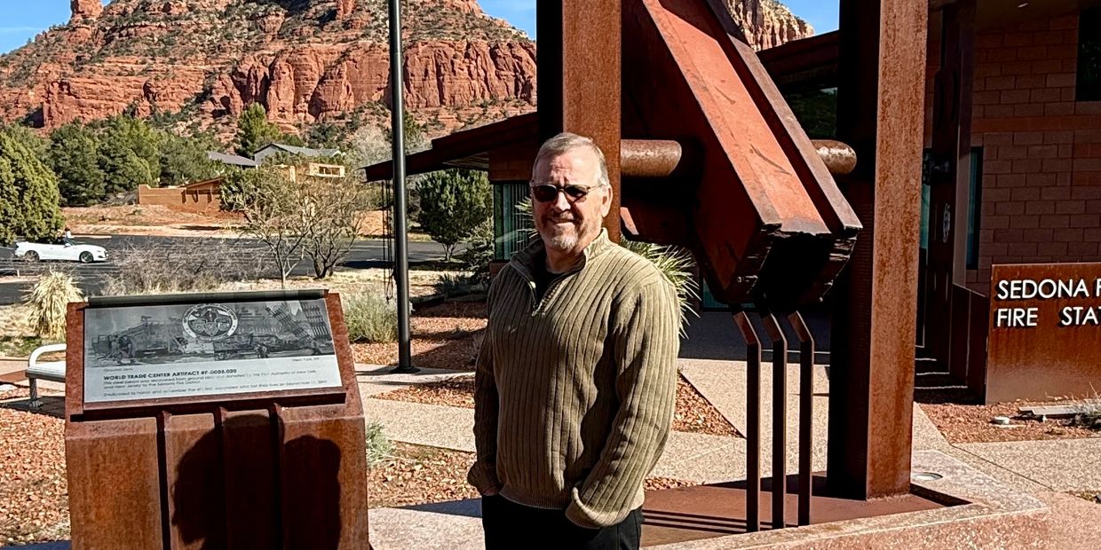 Man standing next to a World Trade Center artifact at Sedona Fire Station.