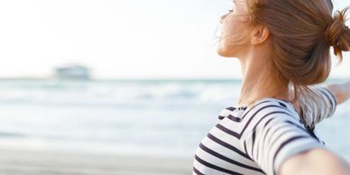 Woman standing near the sea with hands over heart—reflecting inner connection, peace, and emotional 