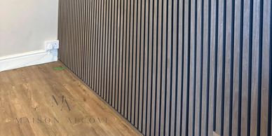 Modern interior wall with vertical slats and wooden flooring.