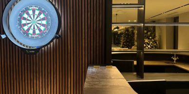 A modern indoor dartboard setup with wooden paneling and a sleek counter.