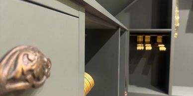 Close-up of a drawer handle on a gray cabinet with empty shelves.