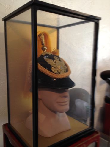 A decorative military helmet displayed in a glass case.