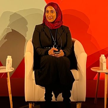 Sam sitting on stage at a panel meeting for Adweek