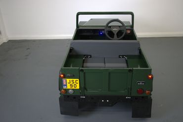 A small green utility vehicle with rear seats and a steering wheel.