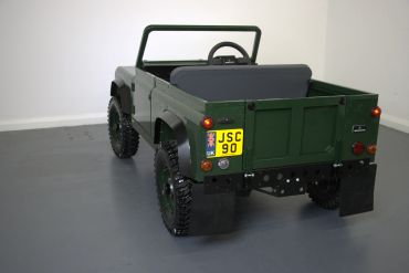 A green miniature off-road vehicle in a white room.